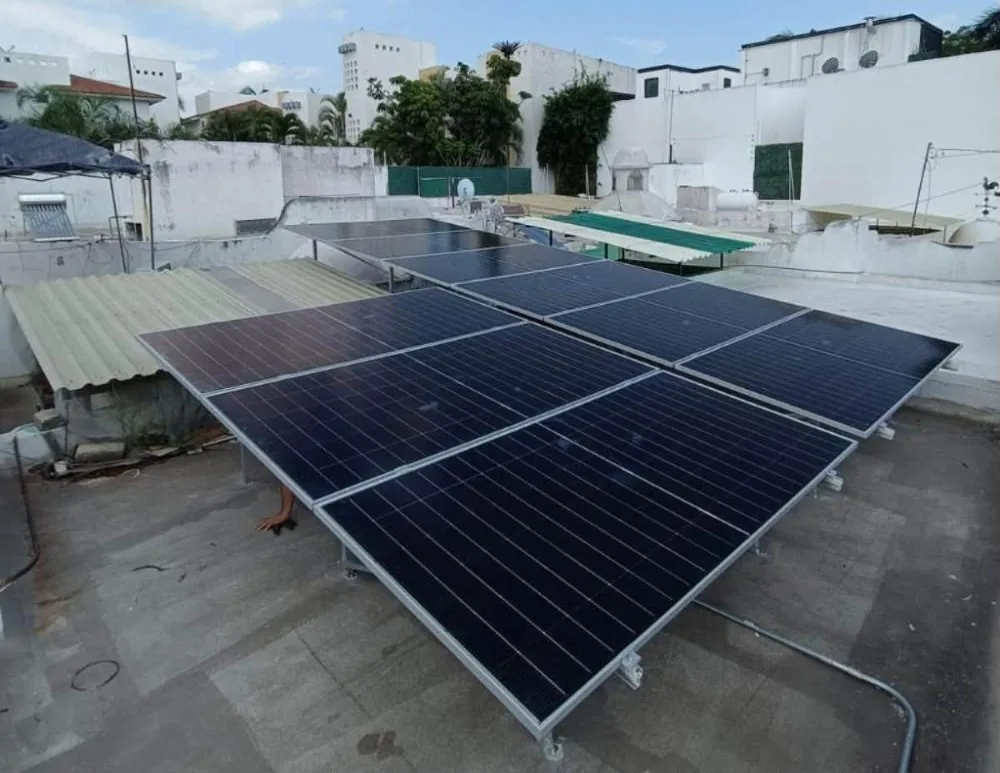 Ocho paneles solares en dos filas sobre una azotea de Colima rodeada de casas blancas