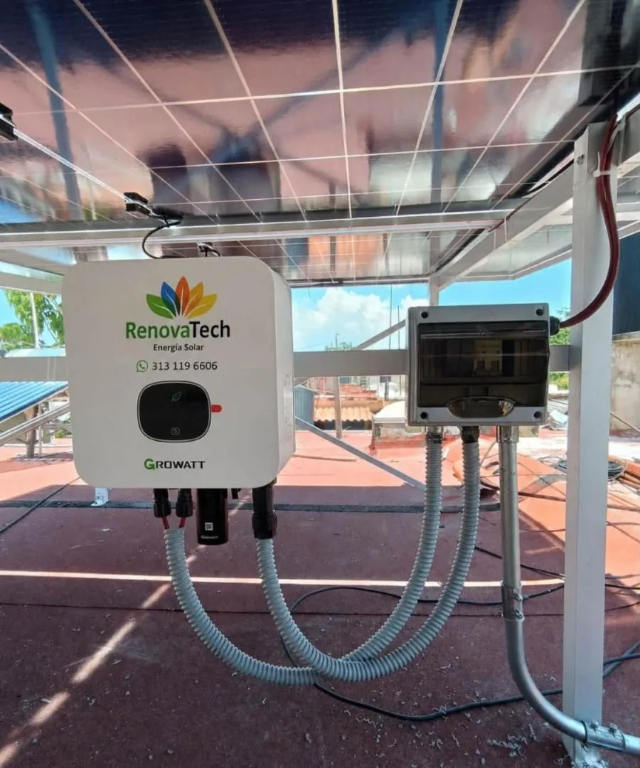 Inversor Growatt con etiqueta de RenovaTech y su caja de protecciones, instalados bajo la estructura de los paneles